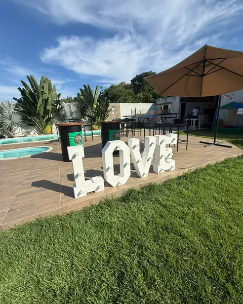 Letreiro luminoso LOVE no gramado, em frente ao deck das piscinas.