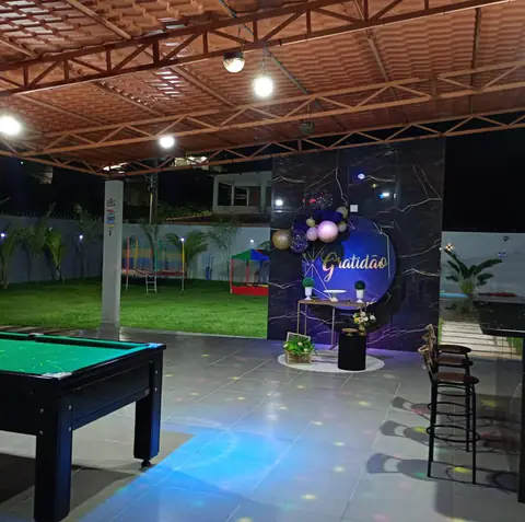 Salão coberto à noite, com painel de mármore escuro decorado com balões e a palavra Gratidão.
